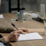 Przedsiębiorca w garniturze podpisuje umowę przy drewnianym biurku