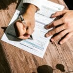 Ręka wypełnia formularz wniosku o pożyczkę na drewnianym biurku