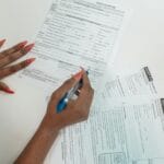 Kobieta z czerwonymi paznokciami wypełnia formularze na biurku