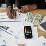 Mężczyzna liczący firmowe finanse przy laptopie, kalkulatorze i banknotach