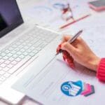 Osoba analizuje na laptopie zestawienie przychodów i kosztów