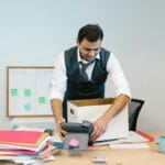 Mężczyzna pakuje rzeczy z biurka w biurze przed zmianą pracy