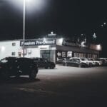 Nocny salon z oświetlonym placem pełnym używanych aut premium