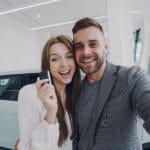 Para robi selfie przy świeżo kupionym samochodzie w salonie