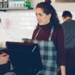 Barista przy ladzie kawiarni obsługuje klienta