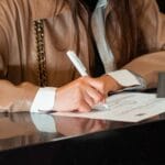 Kobieta podpisuje dokument przy ladzie w biurze rejestracji działalności