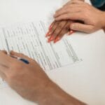 Zbliżenie na ręce podpisujące formularz na białym biurku