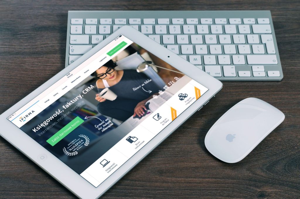 Tablet z otwartą stroną finansową obok białej klawiatur