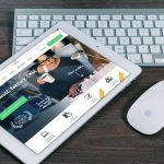 Tablet z otwartą stroną finansową obok białej klawiatur